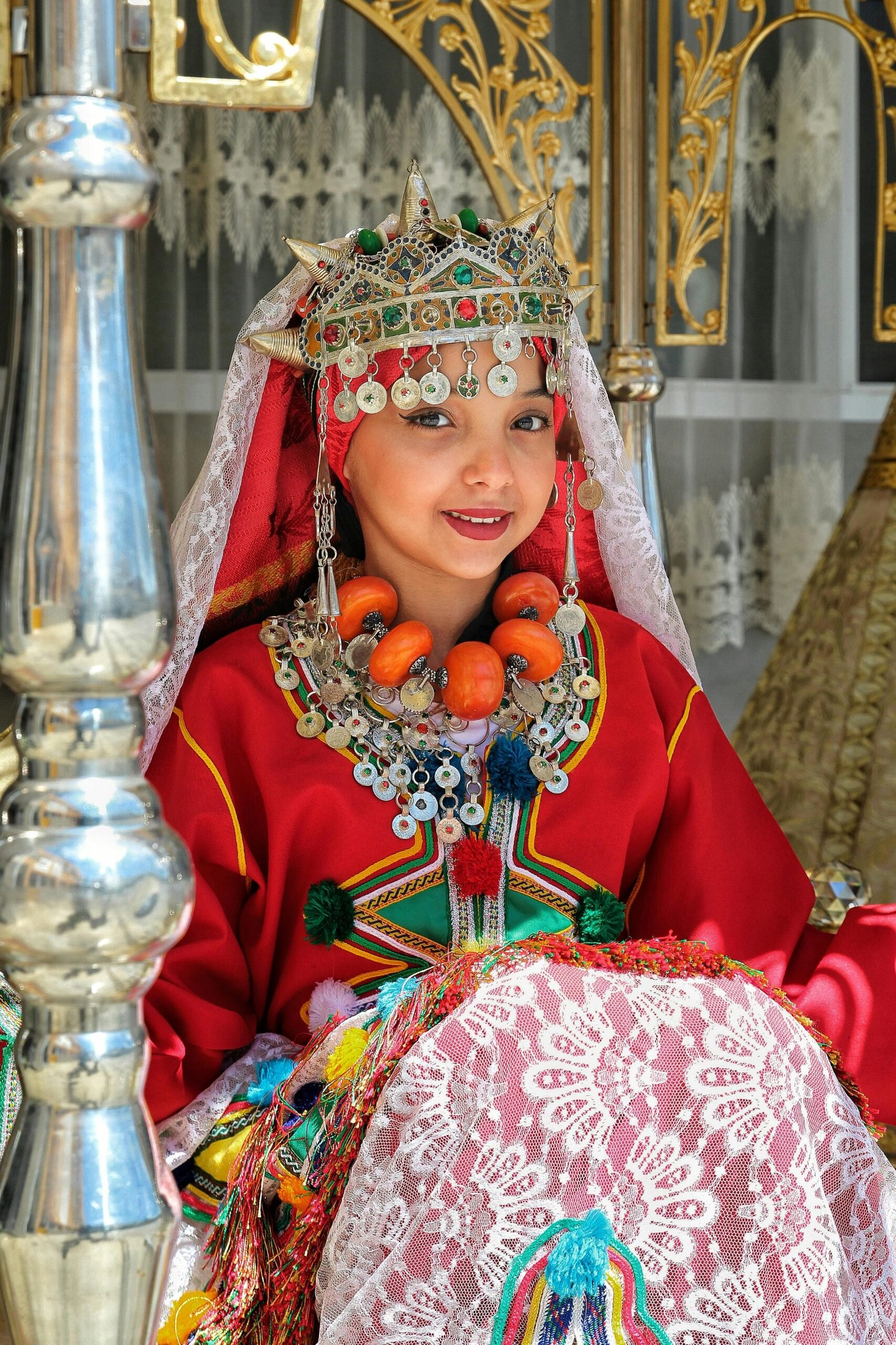 Colorful traditional attire with intricate jewelry and headdress in a cultural setting.