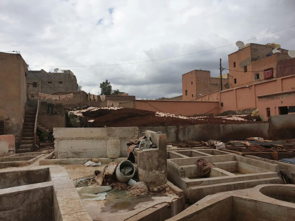 Explore the historic tanneries of Marrakech, showcasing traditional leather processing amidst a cloudy sky.
